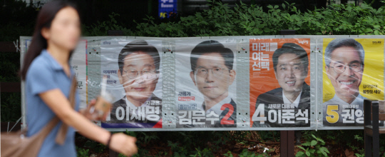 지난 23일 서울 마포구 공덕오거리 인근에 걸린 대선 후보 벽보 앞으로 시민이 지나고 있다. [연합뉴스]